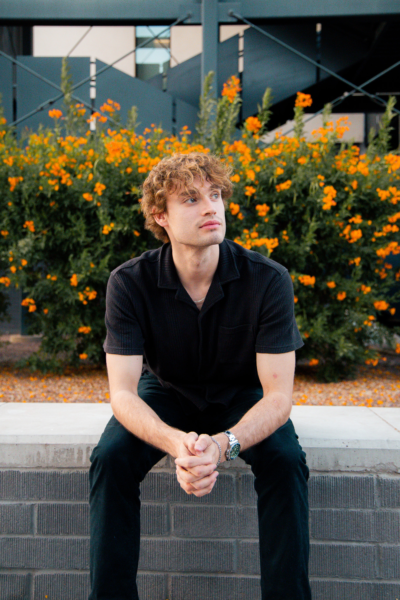 Christian Little seated outdoors beside orange flowers